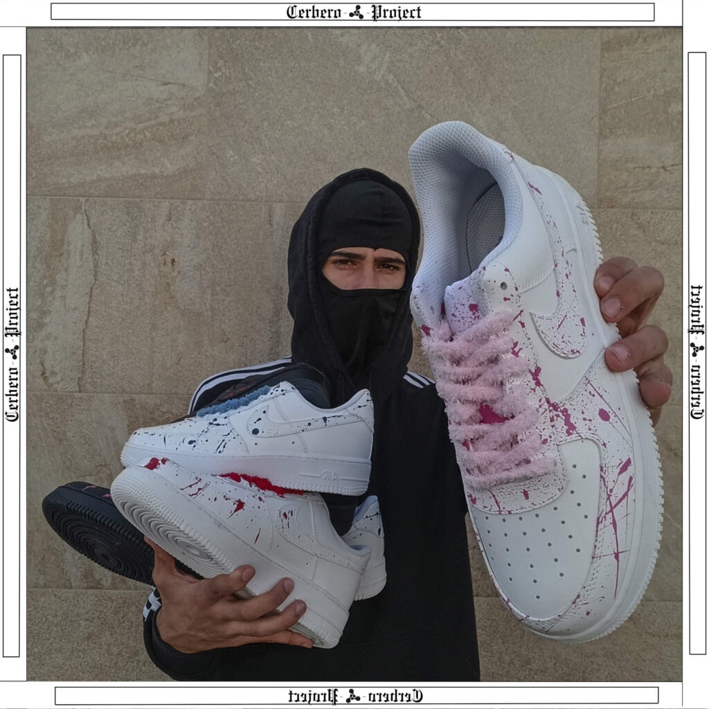 Man holding custom Air Force 1 sneakers with pink rope laces and paint splatter