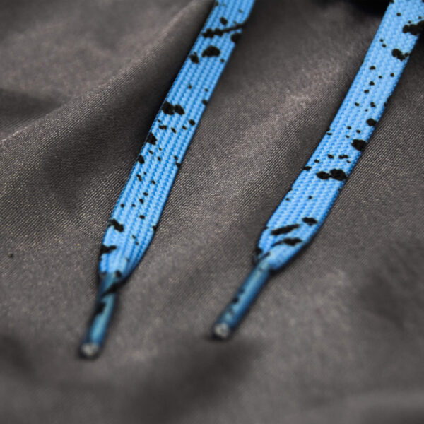 Light blue shoelaces with black paint splatter on a dark gray fabric background