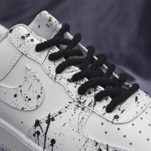 Black rope laces on white sneakers with black paint splatter