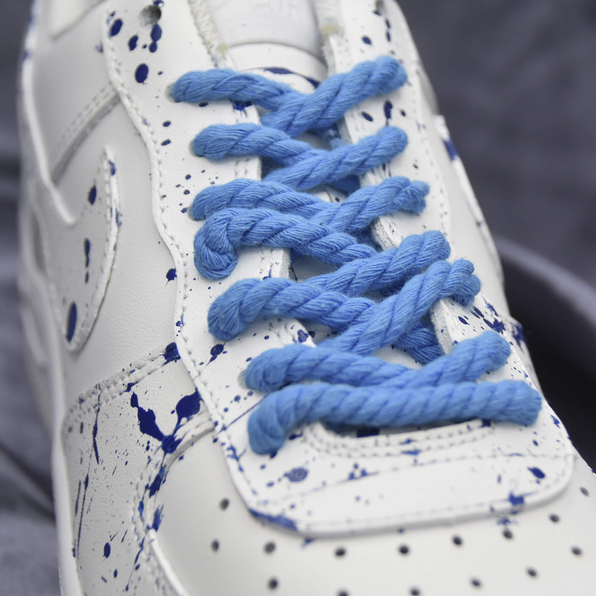 Blue rope laces on a white custom sneaker with blue splatter design