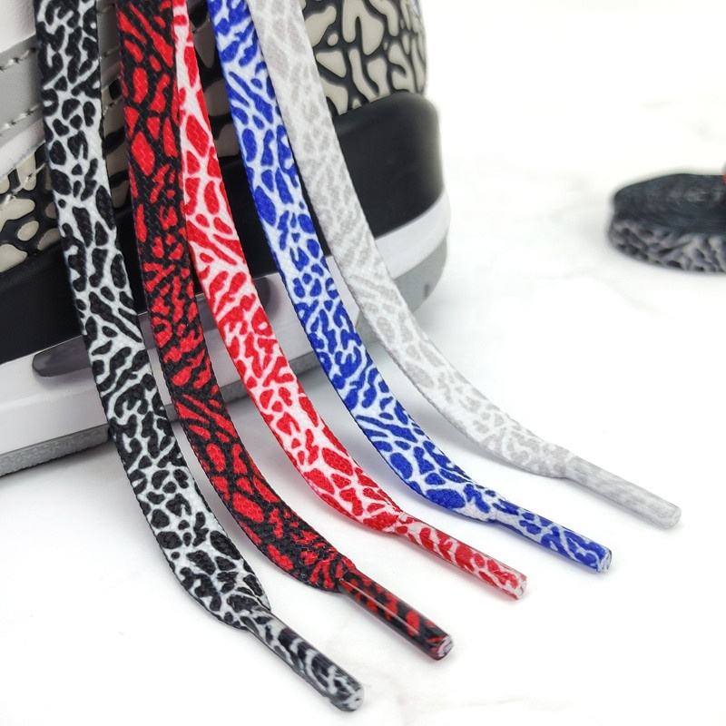 Sneaker with five flat laces in elephant print patterns—black, red, white, blue, and gray