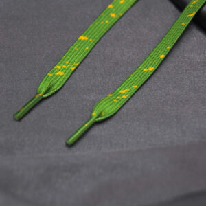 Green shoelaces with yellow paint splatter on gray fabric