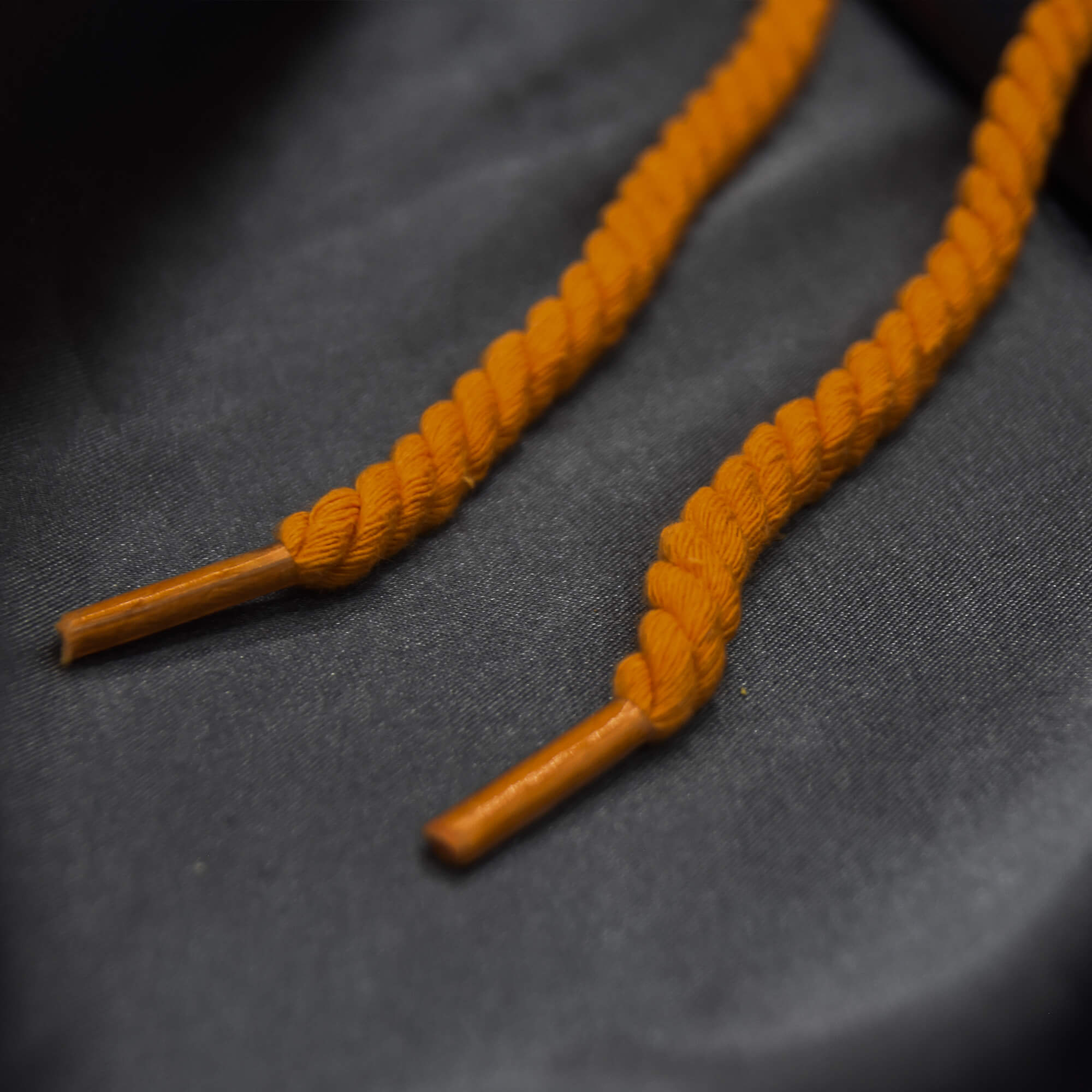 Orange rope laces displayed on gray satin