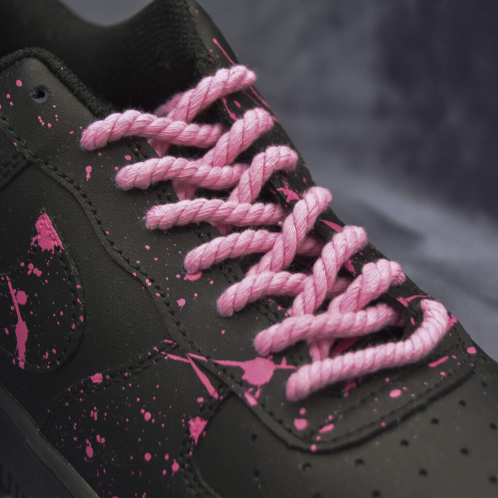 Pink rope laces on black sneakers with pink paint splatter