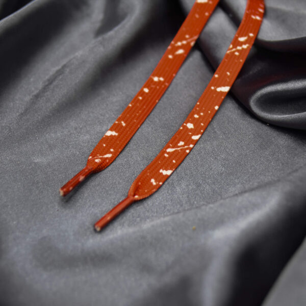 Flat red shoelaces with white paint splatter pattern