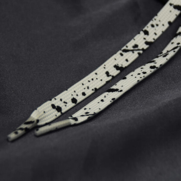 White shoelaces with black paint splatter on dark satin background