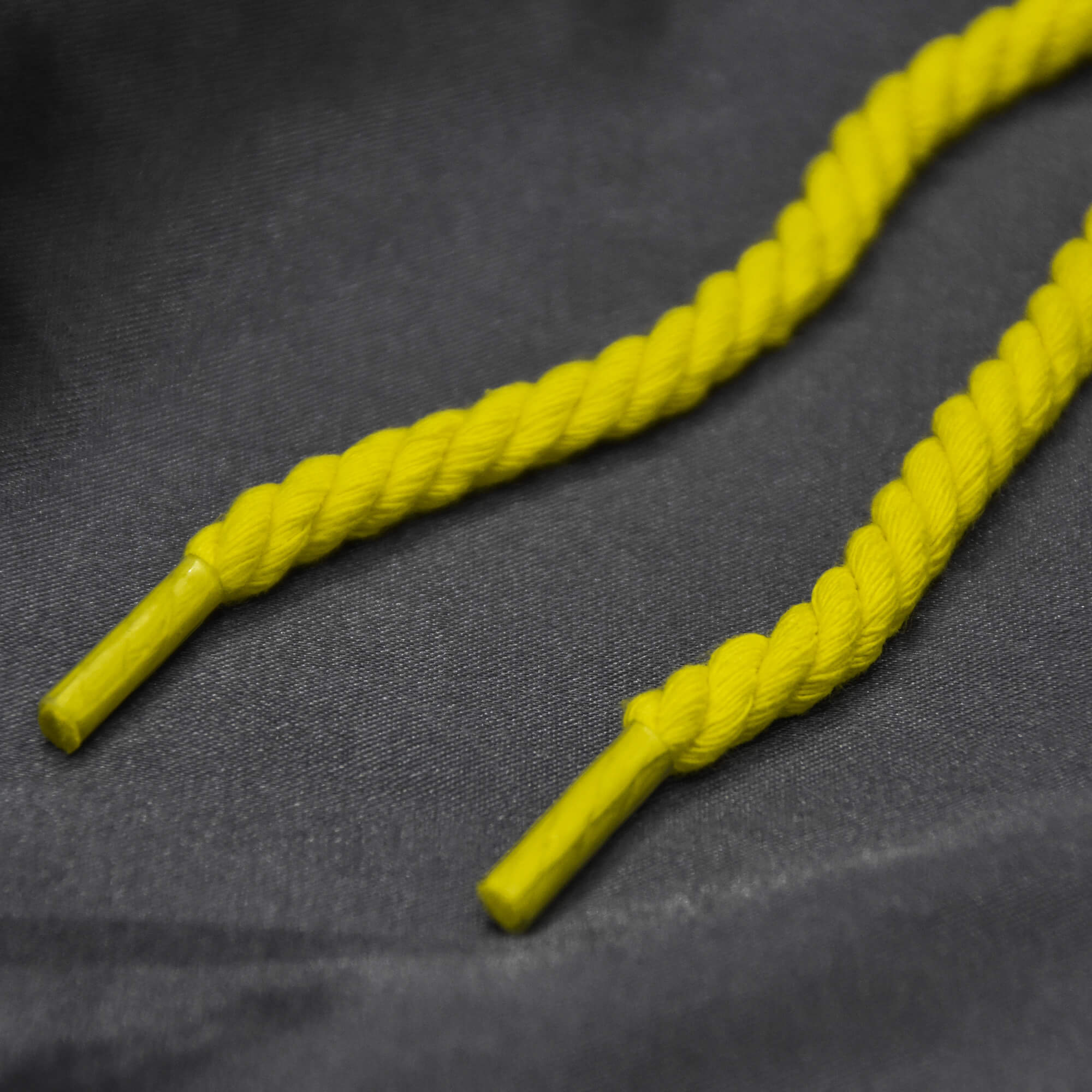 Bright yellow rope laces on dark satin fabric